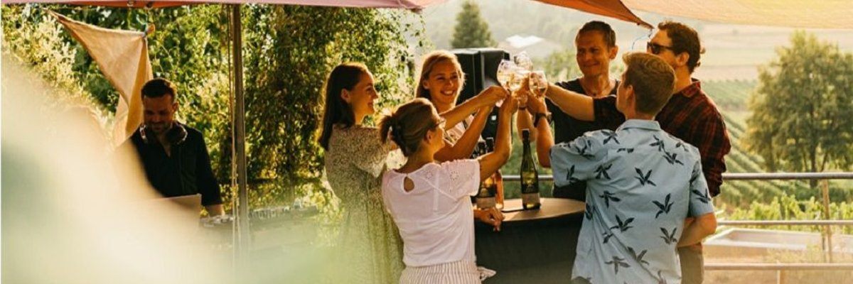 Gesellige Runde bei einer Weinprobe im Weingut unter Sonnenschirm